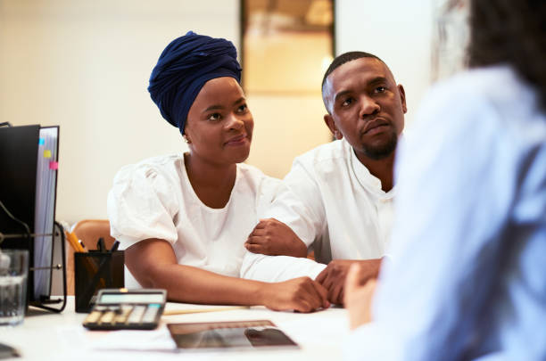 African American couple or clients at a business or finance meeting or doctor consultation sitting at a desk. Black woman and man in a office building, listening to expert advice or advisor talking.
